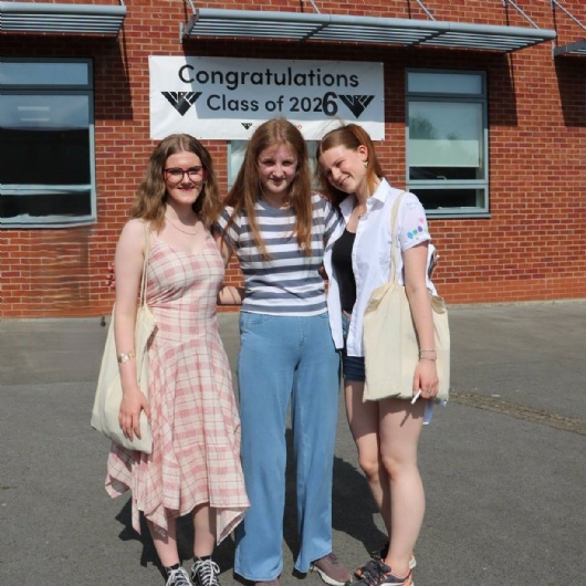 3 students standing under a banner saying congratulations